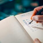 Close-up of a hand writing in a notebook with a checklist for effective task management.